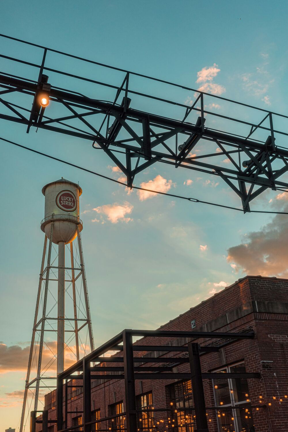 The Lucky Strike water tower above brick buildings in downtown Durham at sunset